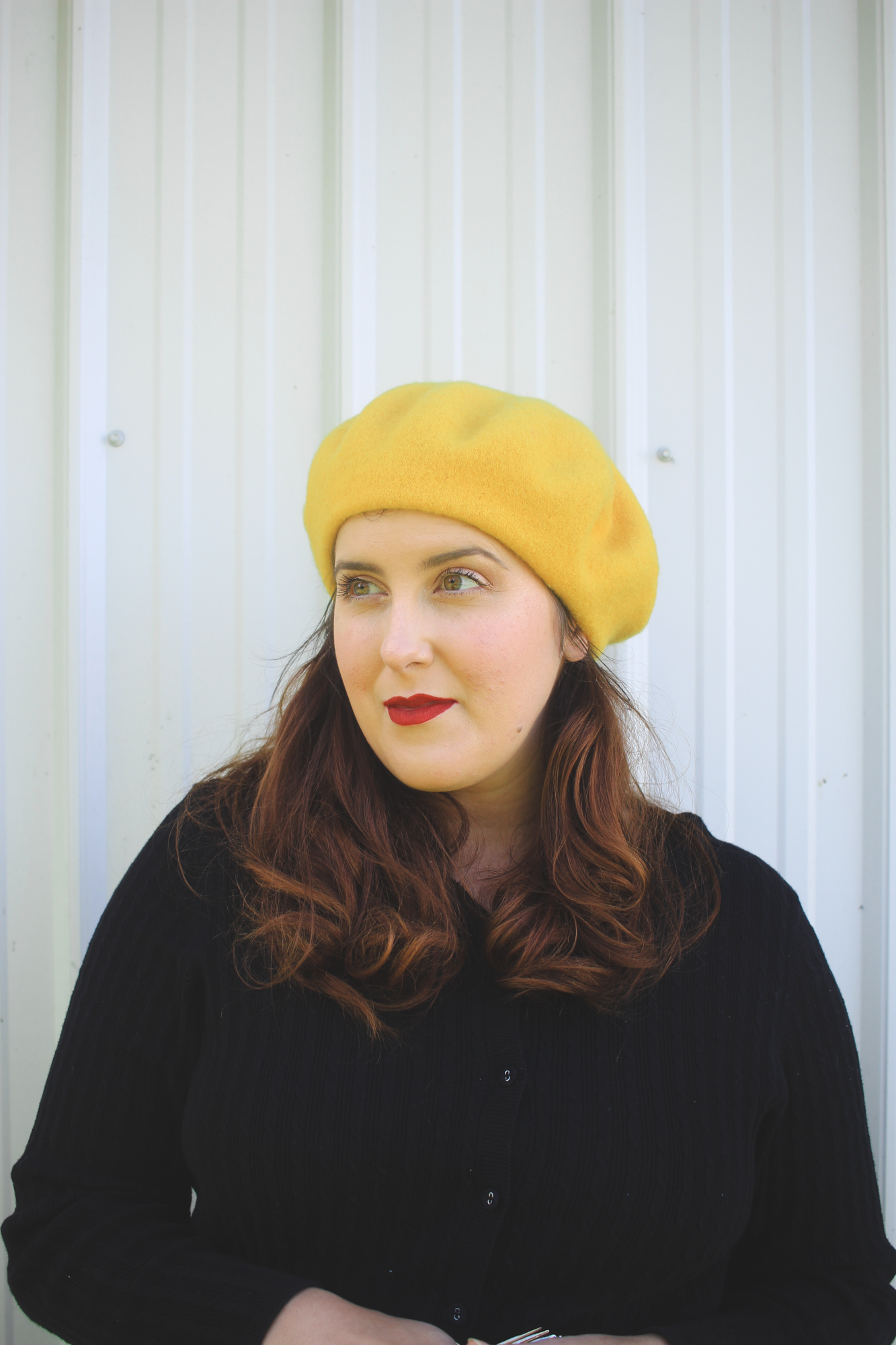 woman with curled hair wearing a yellow beret